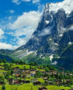 the mountains are covered in snow and green grass, with houses on each side below