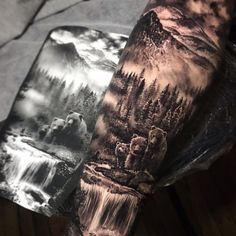 a man's arm with a bear and waterfall tattoo on it