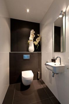 a white toilet sitting next to a sink in a bathroom under a mirror and lights