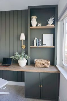 a home office with green painted walls and shelving units on either side of the desk