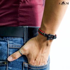 a person wearing a red and black beaded bracelet on their left hand, with the other hand in his pocket