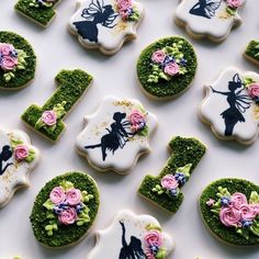 decorated cookies are arranged in the shape of letters and fairy land characters with pink roses on them