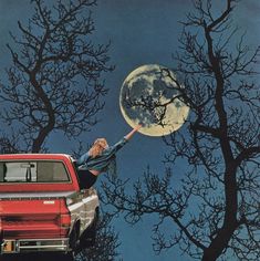 a woman reaching for the moon on top of a red pick up truck in front of trees