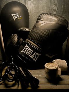 two boxing gloves, one black and one white are sitting on a wooden table next to other sports equipment