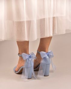 a woman's feet wearing blue shoes with bows