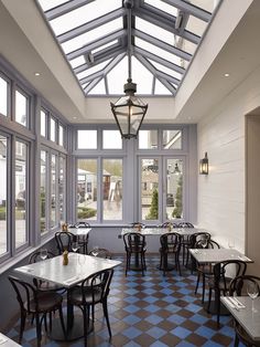 an empty restaurant with blue and white checkered flooring on the walls, tables and chairs in front of large windows