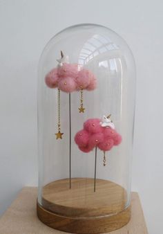 two pink clouds in a glass dome with gold chains and stars hanging from the sides