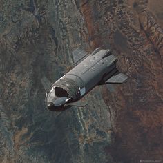 an airplane is flying in the sky over some mountains and land, as seen from above