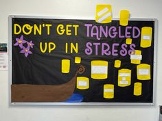 a bulletin board with yellow tape taped to it and words written on the wall above it