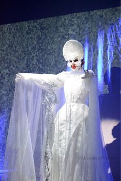 a woman dressed in white is standing on stage