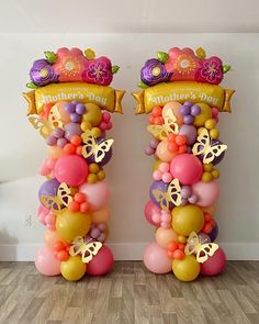 two tall balloons are decorated with flowers and butterflies for a mother's day celebration