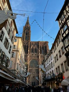 an old cathedral towering over a city filled with tall buildings and people walking down the street