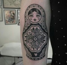 a black and white photo of a russian nesting doll tattoo on the right upper arm