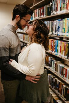 a man and woman standing next to each other in front of bookshelves