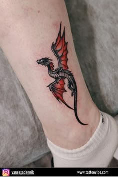 a small dragon tattoo on the ankle is shown in black and grey colors, with red accents