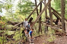 three boys are playing on a wooden structure in the woods