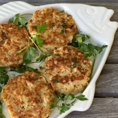 four crab cakes on a white plate with parsley