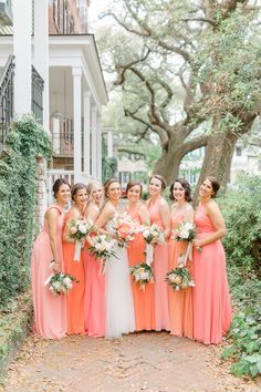 a group of women standing next to each other in front of a building with trees