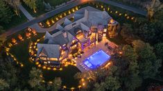 an aerial view of a large home with a pool in the yard and lights around it