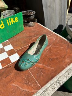 a pair of green shoes sitting on top of a tiled floor next to a sign