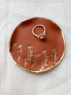 a ring dish with flowers and leaves on it