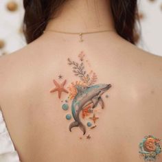 a woman's back with a dolphin and starfish tattoo on her left shoulder