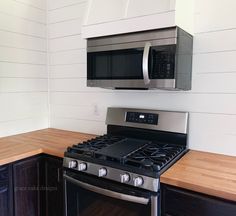 a stove and microwave in a kitchen with wood counter tops on either side of the oven