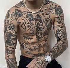 a man with many tattoos on his chest and arm is standing in front of a wall