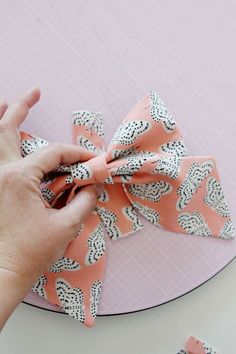 a person is tying a bow on top of a paper plate with pink and white designs