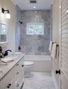 a white bathroom with marble counter tops and walls, along with a toilet and tub