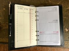 an open planner with a pen on top of it