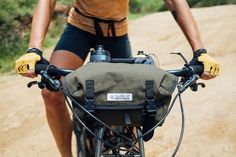 a man riding a bike down a dirt road with gloves on his hands and holding onto the handlebars