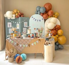 a party with balloons and decorations on the wall in front of a cake table filled with desserts