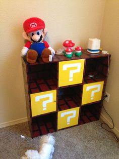 a stuffed animal sitting on top of a wooden shelf next to a nintendo game cabinet