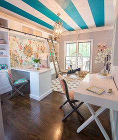 a room that has a desk, chair and ladder in it with blue and white stripes on the ceiling