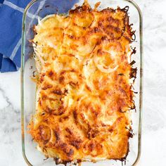 a casserole dish with onions and cheese in a glass baking dish on a marble surface