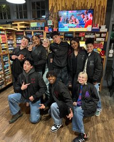 a group of young people posing for a photo in front of a store display case