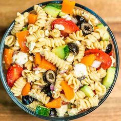 a bowl filled with pasta salad on top of a wooden table