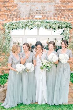 a group of women standing next to each other in front of a building with flowers