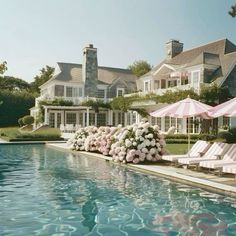 an outdoor swimming pool with lawn chairs and umbrellas next to the water's edge