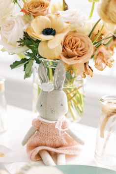 a vase filled with flowers next to a stuffed rabbit on top of a white table