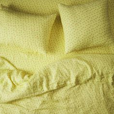 an unmade bed with yellow sheets and pillows