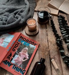 an open book and some glasses on a wooden table next to a cup of coffee