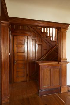 an empty room with wood paneling and stairs