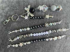 four keychains with charms and words on them sitting on a gray carpeted surface