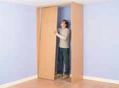 a man is standing in an open closet with his hands on the door and looking up