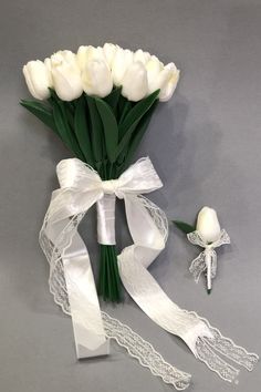 a bouquet of white tulips tied together with ribbon and garter next to it