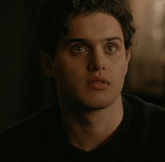 a close up of a person wearing a black shirt and looking at the camera with an intense look on his face