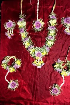 flowers and pearls are arranged on a red cloth