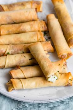 several spring rolls on a white plate with cheese and herbs in the middle, ready to be eaten